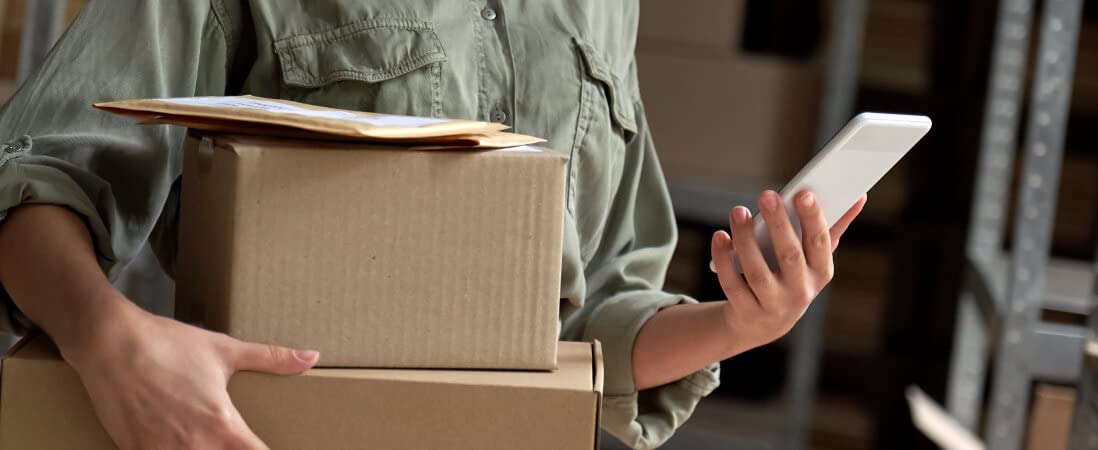 woman holding packages and looking at her phone